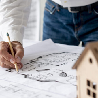 Arquiteto analisando planta baixa para calcular o valor de um terreno e projeto.